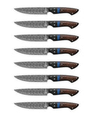 Eight Folded Steel Dahlia steak knives feature AUS10 stainless Damascus blades and dark wood handles with blue accents, neatly arranged in a row on a white background.