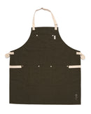 The Folded Steel Chef Apron features eco-friendly rPET canvas in dark green, beige straps, a chest pocket, three lower pockets, and a small white flower on the bottom right—an essential sustainable kitchen accessory.