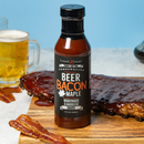 A bottle from Elijah's Xtreme BBQ Bro Box Ultimate Gift Set by Elijah’s Xtreme sits on a wooden board with sauced ribs, crispy bacon, and beer—a mouthwatering BBQ gift set perfect for any grill lover.