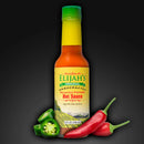 A bottle of Elijah’s Xtreme Roasted Cayenne and Jalapeño Pepper Sauce sits on a dark background, surrounded by fresh sliced jalapeños and whole red chili peppers, emphasizing this flavorful sauce.