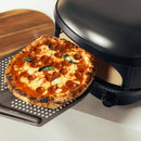 A pepperoni and basil pizza on a perforated metal peel being removed from a Gozney Arc Lite Outdoor Pizza Oven.