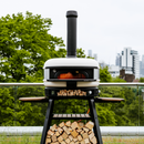 A cylindrical metal Gozney Dome Flue Extension attached to the top of an outdoor pizza oven to provide improved airflow.
