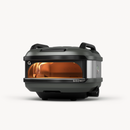 The Gozney Tread Portable Pizza Oven is a compact, modern outdoor oven with a sleek dark gray finish, sturdy top handles, and a glass window revealing the flame—adventure-ready for any outdoor kitchen setup.