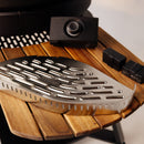 The Gozney Wood-Fire Control Kit by Gozney, featuring a stainless steel grill plate, a black airflow-control knob, and two black rectangular rechargeable batteries, is arranged on a wooden surface.