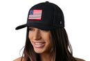 A woman smiles wearing the Haka Hat Betsy Ross Flag Trucker Hat, a black USA snapback featuring a vintage American flag patch.