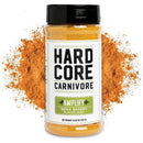 A container of Hardcore Carnivore Amplify Mega Savory Flavor Dust Seasoning sits before a pile of the orange-brown spice. The white label features bold black and green text, showcasing this Hardcore Carnivore umami flavor enhancer.
