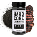 A container of Hardcore Carnivore Black Beef Seasoning by Hardcore Carnivore is shown on a white background, next to a pile of black seasoning and a sliced, charred piece of cooked beef.