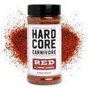 A bottle of Hardcore Carnivore Red seasoning stands upright with a pile of reddish spice behind it. The bold label shows off the Hardcore Carnivore brand—perfect for the BBQ Rub Sampler Set, net weight 11 oz (311 g).