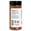 A plastic jar of Hardcore Carnivore Red All Purpose Seasoning with a black screw-top lid. The label by Hardcore Carnivore describes it as a Texas-inspired BBQ rub and competition seasoning for pork and chicken, with ingredients and usage instructions.