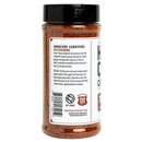 A plastic jar of Hardcore Carnivore Red All Purpose Seasoning with a black screw-top lid. The label by Hardcore Carnivore describes it as a Texas-inspired BBQ rub and competition seasoning for pork and chicken, with ingredients and usage instructions.
