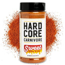 A bottle of Hardcore Carnivore Sweet BBQ Rub by Hardcore Carnivore is featured with a pile of its reddish-orange seasoning behind it, showcasing its bold barbecue flavor. The white label displays bold black and red lettering.