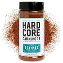 A jar of Hardcore Carnivore Tex-Mex Taco and Fajita Seasoning with a teal label sits surrounded by a burst of reddish-brown spices.