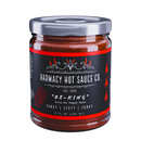A 9oz glass jar of Harmacy Hot Sauce Co. Ox-King Extra Hot Kimchi Sauce features a black label with red accents, flame illustrations, and notes Tangy | Zesty | Funky. Made with superhot peppers.
