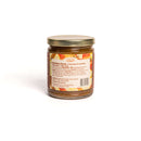 A glass jar of In The Curious Kitchen Bourbon Apple Butter, topped with a gold lid and labeled with nutrition facts and ingredients. Ideal for charcuterie boards or Southern entertaining, shown on a white background.