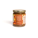 In The Curious Kitchen Bourbon Apple Butter comes in a glass jar with a gold lid. Crafted with tart local apples, warm spices, and bourbon, it’s ideal for charcuterie boards or entertaining. The detailed label displays partial nutritional facts.