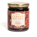 A 9oz glass jar of bourbon-infused cherries from In The Curious Kitchen, featuring a gold lid and rich red label with cherry images. Part of the Bourbon-Infused Gourmet Gift Set—made with Kentucky bourbon, perfect for gifting.