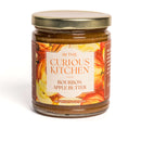 A glass jar with a gold lid labeled In The Curious Kitchen Brunch & Breakfast Jam Trio. This 9-ounce jar is part of our handcrafted fruit spreads—ideal for anyone who enjoys Southern-inspired breakfast jams.