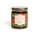A glass jar from the In The Curious Kitchen Entertaining Jam & Jelly Gift Set, with a gold lid and colorful pepper-themed label—ideal for charcuterie boards or Southern spreads. Net weight: 9 oz (255g). Brand: In The Curious Kitchen.