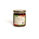 A glass jar with a gold lid holds In The Curious Kitchen Hot Pepper Jelly. Handcrafted in Kentucky, it features nutrition facts and ingredients on the back label. The jar is shown on a white background, with brand and product name not visible.