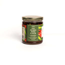A glass jar with a gold lid holds In the Curious Kitchen Hot Pepper Jelly by In The Curious Kitchen. Its front label reads “Jam Packed With Flavor” in green, red, and white. This small batch Kentucky treat is shown on a plain white background.