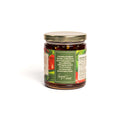 In The Curious Kitchen Hot Pepper Jelly comes in a glass jar with a gold lid. Its green label, handcrafted in Kentucky, features sweet bell peppers, jalapeños, savory seasonings, and the nutrition label peeking through.