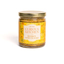 A glass jar from In The Curious Kitchen, featured in the Southern Charcuterie Spread Bundle, with a gold lid and yellow label—perfect for gifting or adding southern flavor to your next charcuterie board.