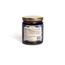 A glass jar of In The Curious Kitchen blueberry preserves with a gold lid, shown from the back with nutrition and ingredient labels. Dark purple contents; ideal for charcuterie or the Southern Gourmet Spread Gift Set. White background.