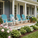 A charming front porch features four Kanyon Living Adirondack Rocking Chairs in Aruba Blue & White, white columns, potted ferns, blooming hydrangeas, string lights above, and a garden of pink and white flowers with green hostas.