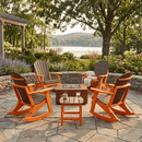 Six Kanyon Living Adirondack Rocking Chairs in Dark Wood & Orange surround a square fire pit on a stone patio. A small table holds two glasses, with lush greenery and a lake visible in the sunny background.