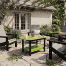 A cozy patio features four cushioned chairs around the Kanyon Living Poly Lumber Oval Coffee Table in lime green & black, set on a stone patio with lush plants, lavender, string lights under a pergola, and French doors in the background.