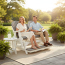 A smiling couple enjoys a sunny garden on the Kanyon Living Poly Lumber 5′ Adirondack Glider Tall Version Deluxe in Driftwood Grey and White. She holds a drink, he has a book, and lemonade sits on the table by their outdoor furniture.