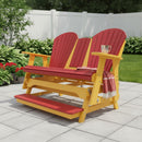 The Kanyon Living Poly Lumber 5′ Adirondack Glider Tall Version in red and yellow sits on a patio, with a glass of water and striped blanket on the armrest, surrounded by green plants, red flowers, and a white fence for a welcoming outdoor retreat.