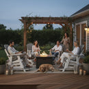 Five adults enjoy a cozy evening on Kanyon Living Poly Lumber Adirondack Glider Chair Tall Deluxe in Driftwood Grey and White, chatting around a fire pit under string lights, while a dog relaxes nearby on the wooden patio.