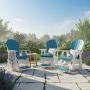 Three Kanyon Living Poly Lumber Adirondack Glider Chairs in Tall Aruba Blue & White are arranged on a stone patio with blooming flowers and greenery. A small table with drinks sits between the chairs under a clear blue sky.