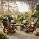 Four Kanyon Living Poly Lumber Adirondack Glider Chair Talls in Black and Deluxe Antique Mahogany surround a square table on a stone patio, creating an inviting outdoor set beneath a pergola with flowers, wisteria, and scenic trees.
