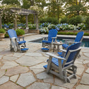 Four Kanyon Living Poly Lumber Adirondack Glider Chair Tall Blue and Light Grey chairs surround a small table on a stone patio by a pool, with greenery, flowering bushes, and a wooden pergola nearby. A blanket is draped over one eco-friendly chair.