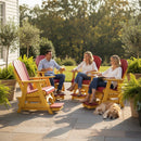 Three adults relax on Kanyon Living Poly Lumber Adirondack Glider Chair Tall in red and yellow by Kanyon Living on a sunny patio with green plants. A golden retriever lies nearby, with trees in the background.