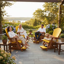 Three adults relax on Kanyon Living Poly Lumber Adirondack Glider Chair Tall Yellow and Cedar Wood by Kanyon Living, surrounded by flowers and greenery. A golden retriever lounges on one chair. The scene is bright, peaceful, with a lake and trees in the background.