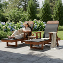 A woman in a sunhat relaxes outdoors, reading on the Kanyon Living Poly Lumber Chaise Lounge with Arms (Black and Deluxe Antique Mahogany) amid hydrangeas, showcasing Kanyon Living’s eco-friendly patio furniture in the sunny garden.