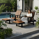 A woman in a white robe relaxes by the pool on the Kanyon Living Poly Lumber Chaise Lounge with Arms Deluxe in Antique Mahogany and Black, reading a book. Lush greenery surrounds her, with another lounge chair on the stone patio for outdoor comfort.