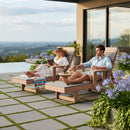 A woman reads and a man relaxes with a drink on Kanyon Living Poly Lumber Chaise Lounges with arms in light grey and weathered wood, surrounded by purple flowers, with scenic views and a modern house in the background.