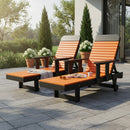 Two Kanyon Living Poly Lumber Chaise Lounges with Arms in orange and black sit on a sunny patio near potted plants. One has a light blanket draped over it, while the other holds an open book, creating an inviting space for outdoor relaxation.