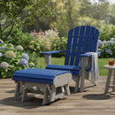 A Kanyon Living Poly Lumber Gliding Ottoman in Blue and Light Grey sits on a wooden deck beside Amish-crafted outdoor furniture. A small table holds a drink and book, while green bushes and colorful flowers brighten the scene.