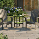 Two gray Adirondack chairs rest on a stone patio with the Kanyon Living Poly Lumber Tall Oval Side Table in lime green and black between them, holding an open book, eyeglasses, and a drink. Lush garden plants and flowers brighten the background.