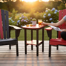 At sunset, a person relaxes on a deck in two red and black Kanyon Living poly lumber chairs flanking the Kanyon Living Poly Lumber Tall Oval Side Table Red and Black, which holds sunglasses, a potted plant, and a book; hydrangeas bloom behind.