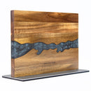 A double-sided magnetic knife holder made from acacia wood, featuring a striking blue/grey resin river design across the middle, stands upright on a flat black base. This elegant knife block by DDR BBQ Supply securely displays your knives using built-in magnetic strips, with the brand name engraved near the bottom center.
