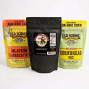 Three bags stand upright: Meat Church's Chili & Cornbread Comfort Bundle is displayed, with Jalapeño Cornbread Mix on the left, classic Cornbread Mix on the right, and a black Meat Church Chili Seasoning bag in the center.