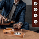 A man in a suit pours whiskey beside the DDR BBQ Supply Multifunction Cigar & Whiskey Gift Set Stand with Ashtray and Drawer—crafted from quality wood, durable, easy to clean, and ideal as a premium cigar and whiskey gift set.