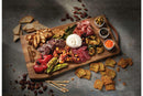 The Napoleon Grills Napoleon Charcuterie Board (70112) features assorted meats, cheeses, grilled vegetables, olives in ceramic ramekins, dips, crackers, and toasted bread slices arranged on a stylish gray surface.