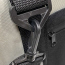 Close-up of a black plastic carabiner clip attached to a black strap on the Polar Bear 12 Pack Original Nylon Soft Cooler by Polar Bear Coolers, with a partially visible zipper on the right side.